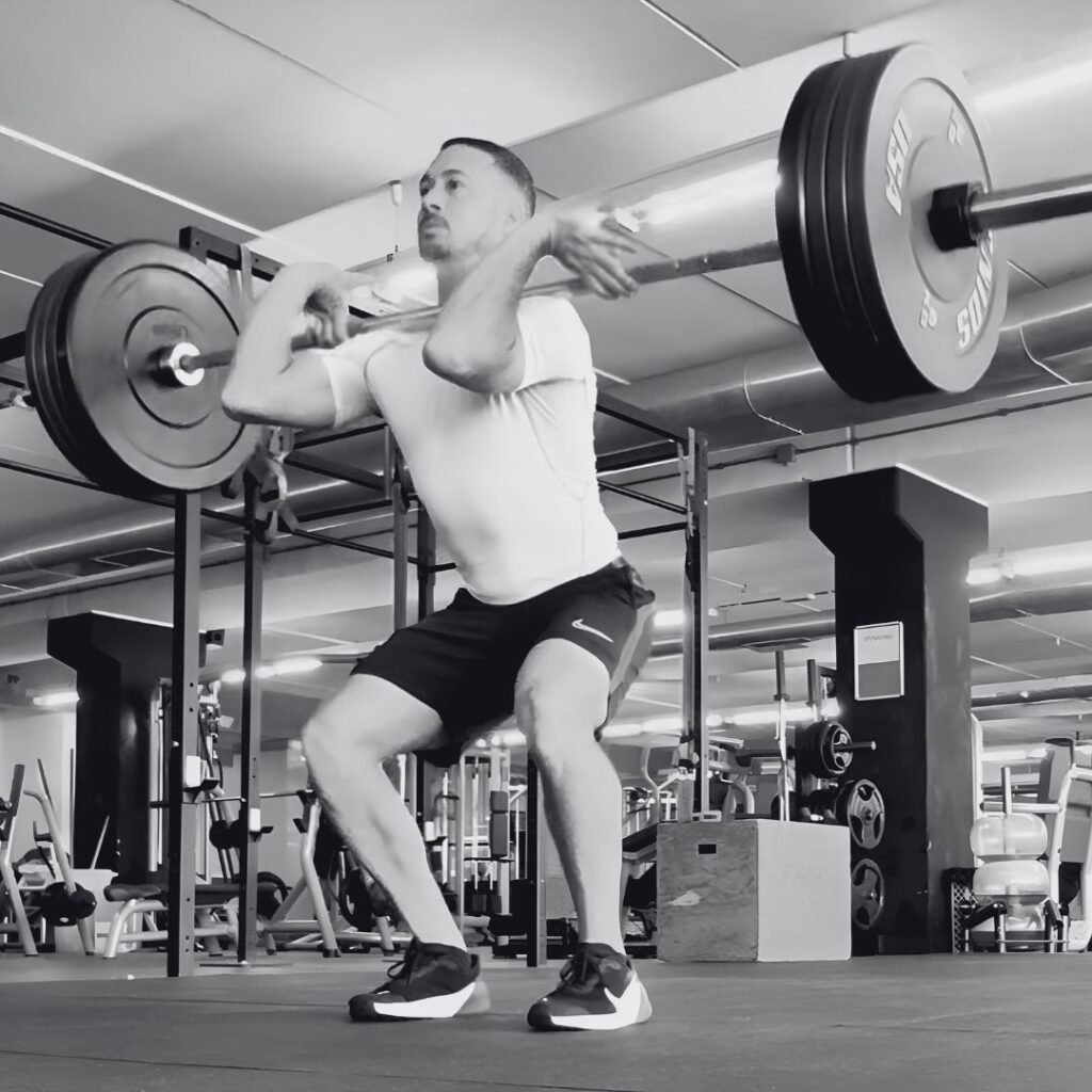 Hombre haciendo una sentadilla frontal con barra en una sala de entrenamiento
