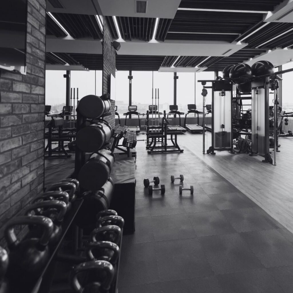 Sala de entrenamiento con mancuernas y una persona entrenando al fondo